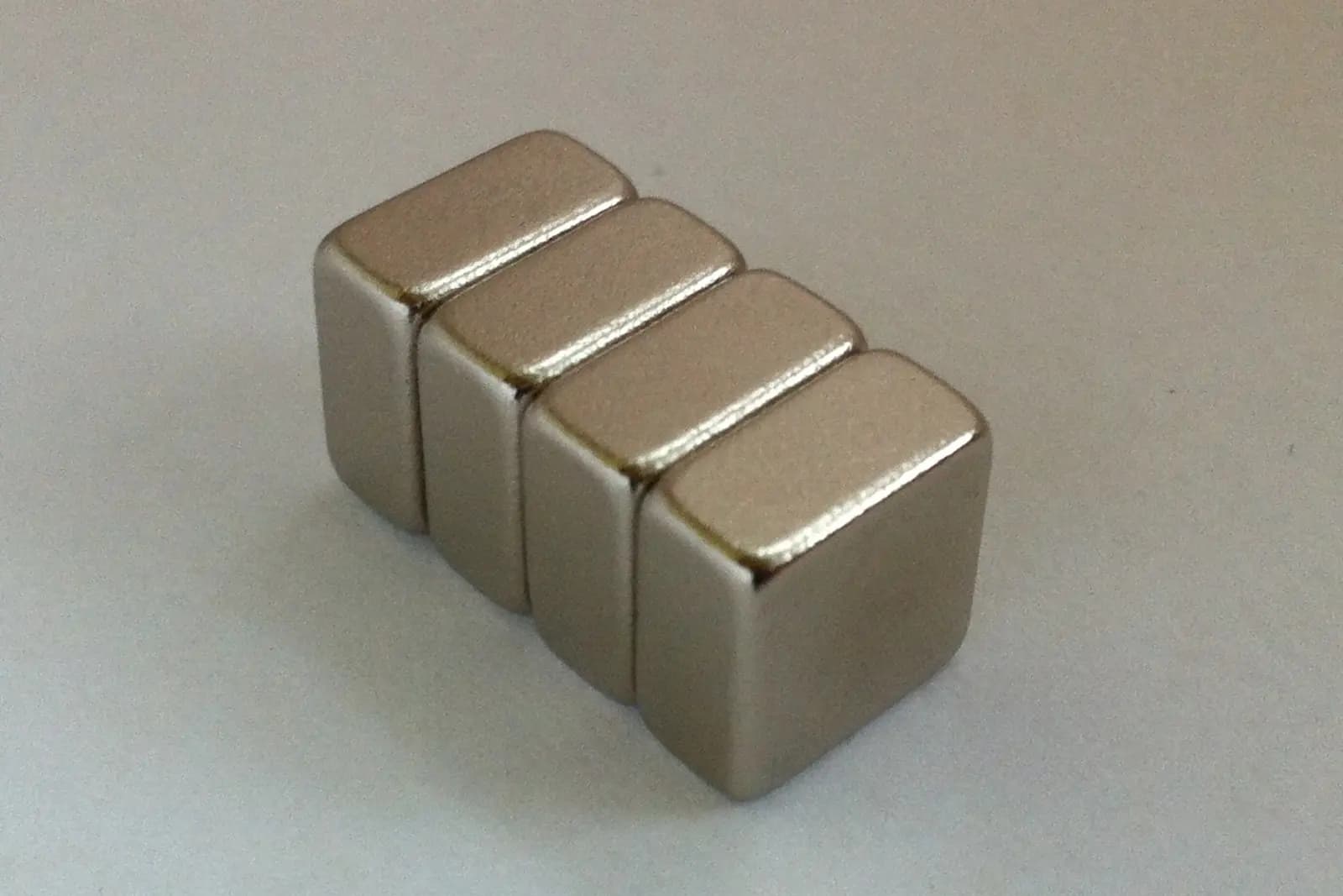 Four representative nickel-plated permanent block magnets arranged in a row